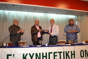 Η στιγμή της απονομής τιμητικής πλακέτας στον κ. Κοντάκο από τον Πρόεδρο της Γ΄ ΚΟΠ κ. Γραμματσούλια. Αριστερά διακρίνεται ο Γεν. Γραμματέας κ. Παπαδάτος και δεξιά το μέλος του ΔΣ κ. Καλλιάνος Ιωάννης.